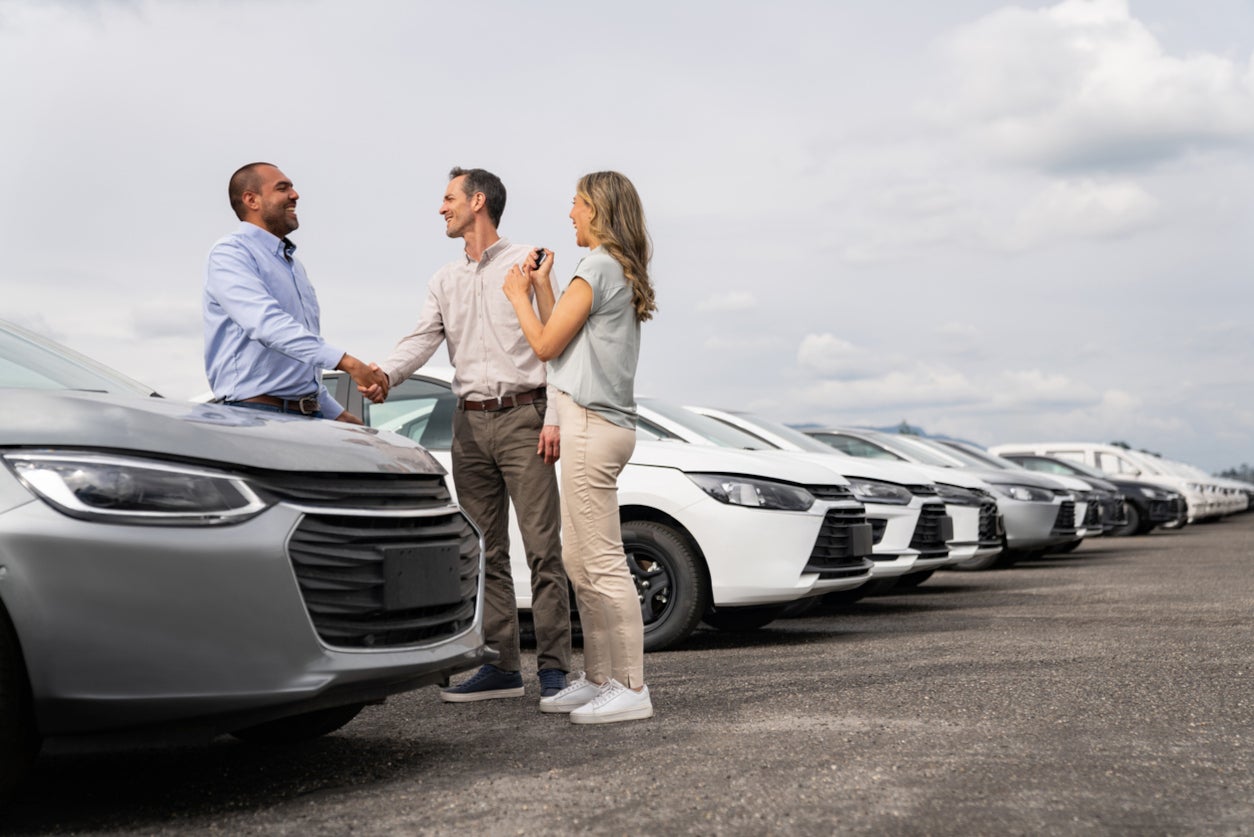 Customers shaking hands with Gunn Chevrolet Salesperson surrounded by vehicles